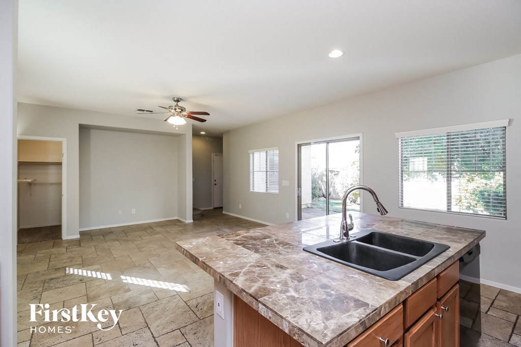 an empty kitchen with a sink and a ceiling fan