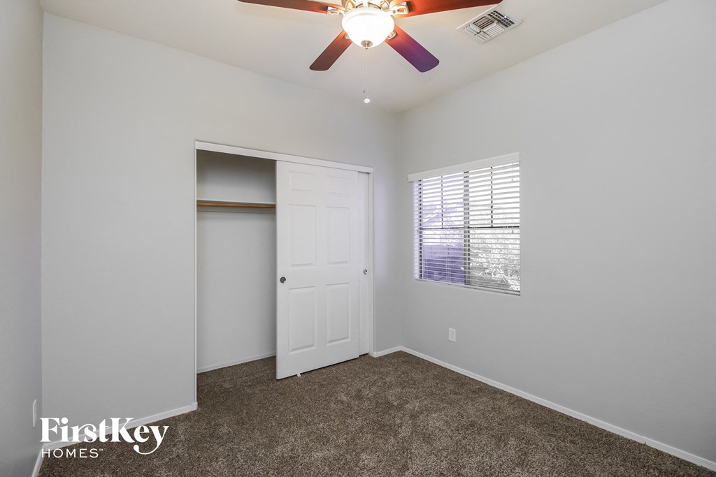 a bedroom with a ceiling fan and a closet