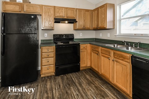A kitchen with wooden cabinets and a black fridge.