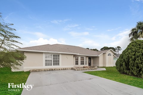 a beige house with a driveway and a palm tree