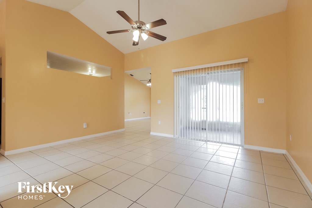 an empty living room with a ceiling fan and a window