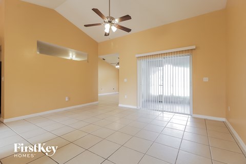 an empty living room with a ceiling fan and a window