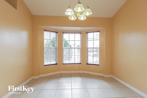 an empty dining room with three windows and a chandelier