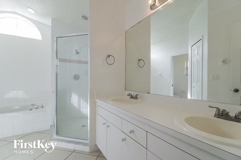 a white bathroom with two sinks and a shower