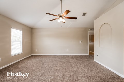the spacious living room with ceiling fan and carpet