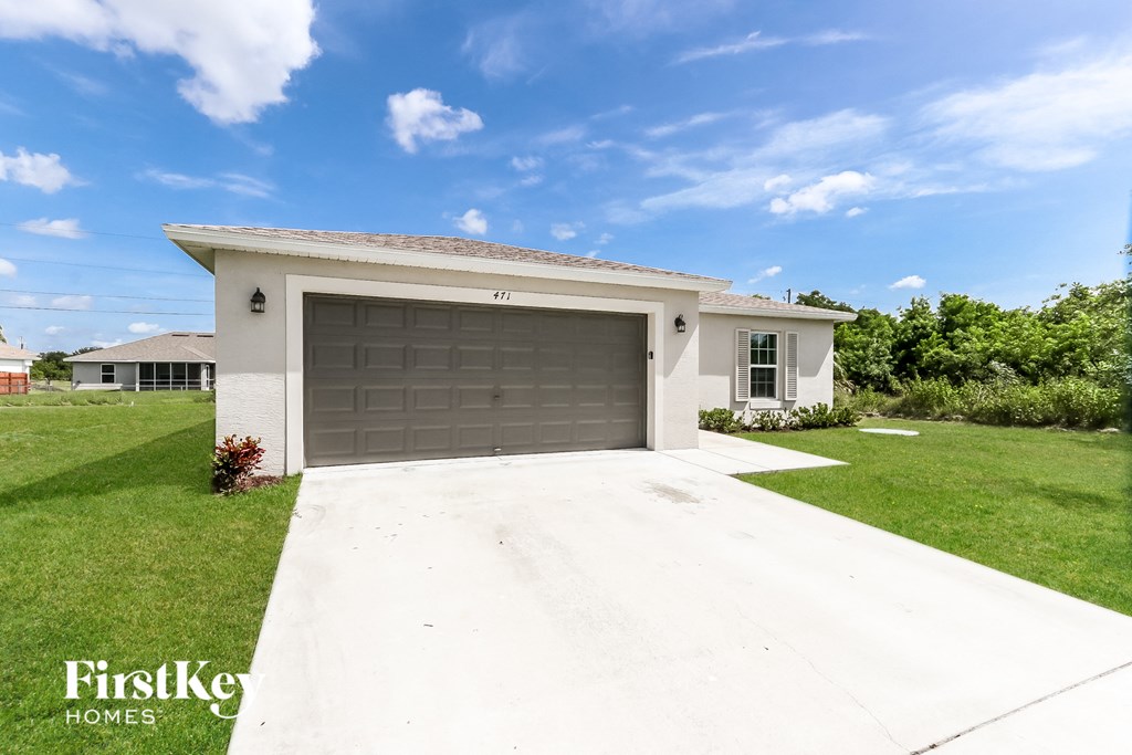 a white house with a garage door and a lawn