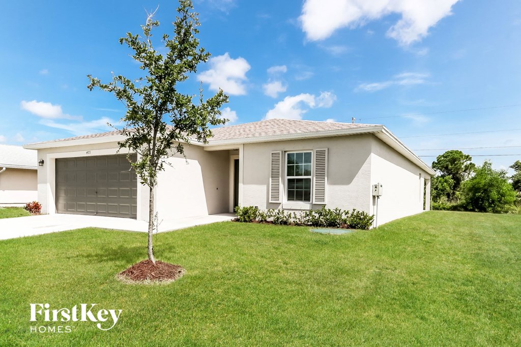 a white house with a lawn and a tree