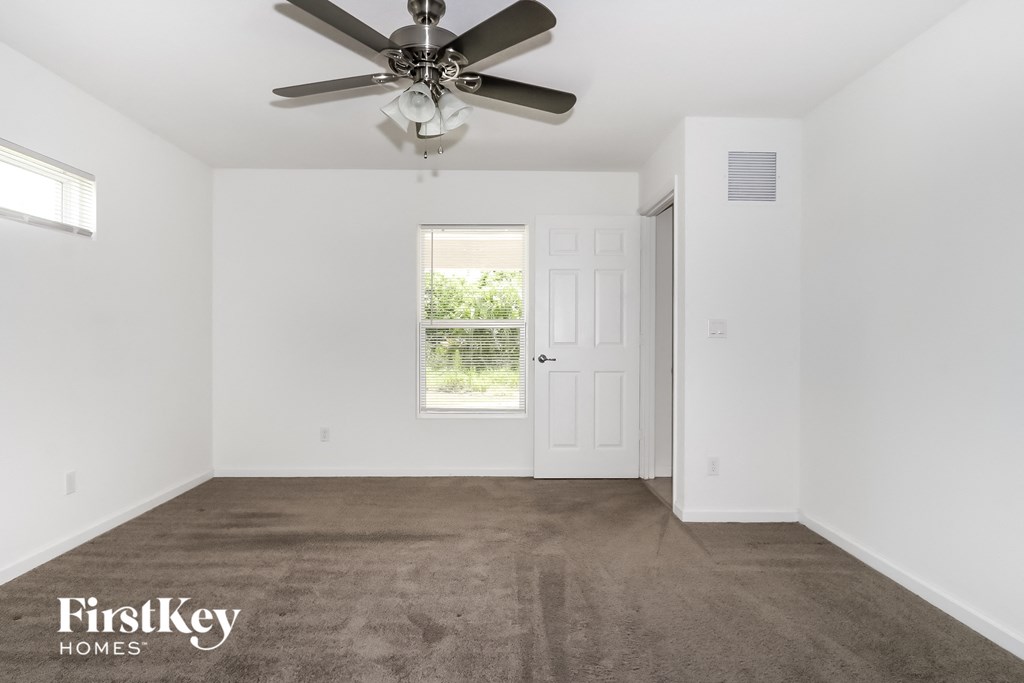 a living room with carpet and a ceiling fan