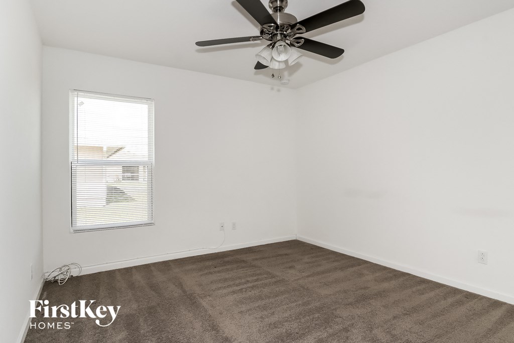 a living room with a ceiling fan and a carpet