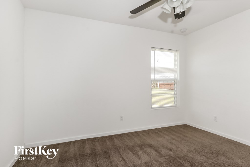 a living room with white walls and a ceiling fan