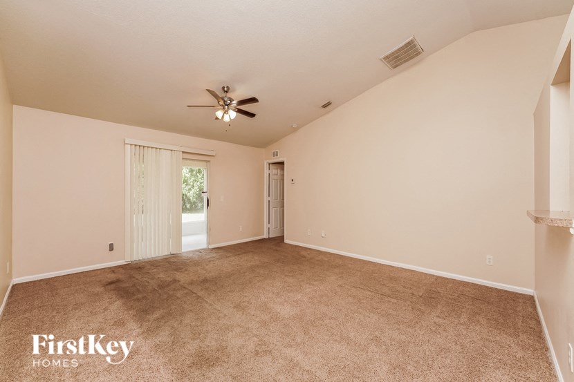 a spacious living room with carpet and a ceiling fan