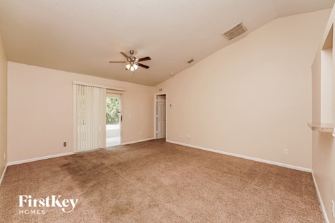 a spacious living room with carpet and a ceiling fan