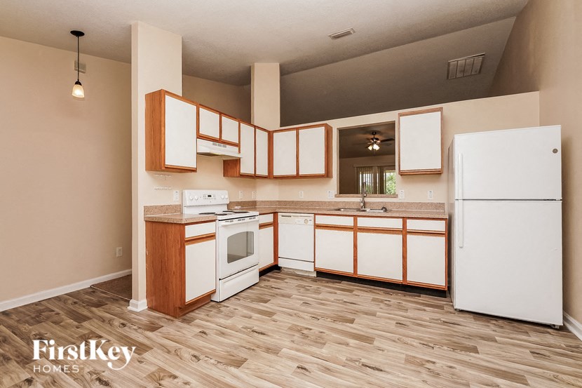 an empty kitchen with white appliances and wooden cabinets
