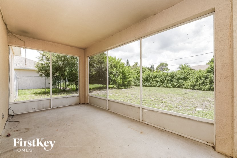 an empty living room with large windows overlooking a yard