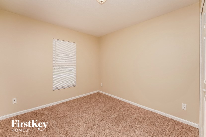 the upstairs bedroom has a carpeted floor and a window