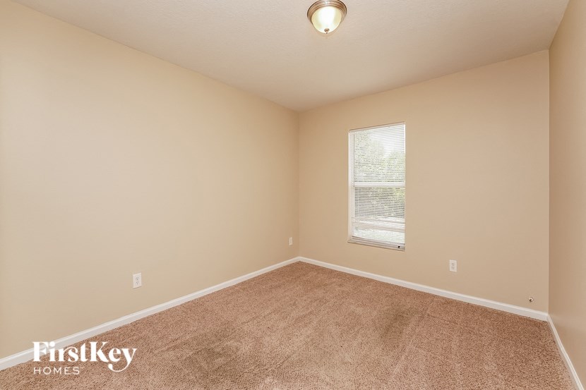 the spacious living room with carpeting and a window