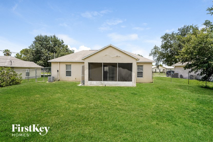 a small beige house with a grassy yard and a fence