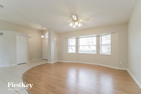 an empty living room with wood floors and a ceiling fan