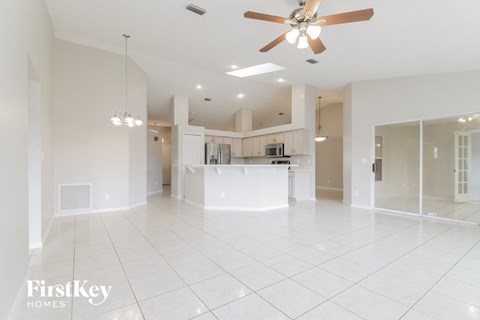 an empty living room and kitchen with a ceiling fan