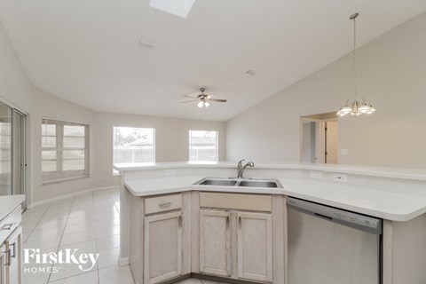 an empty kitchen with a sink and a ceiling fan
