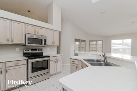 a white kitchen with stainless steel appliances and white counter tops