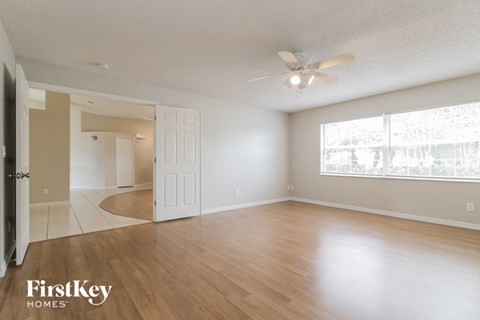 an empty living room with wood floors and a ceiling fan
