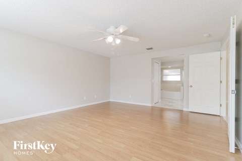 a spacious living room with hardwood floors and a ceiling fan