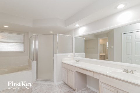 a white bathroom with a large mirror and a shower and a sink