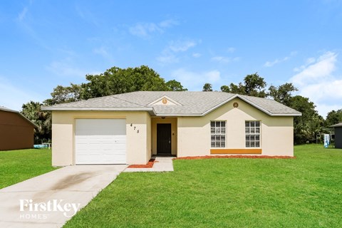 a beige house with a garage and a green lawn