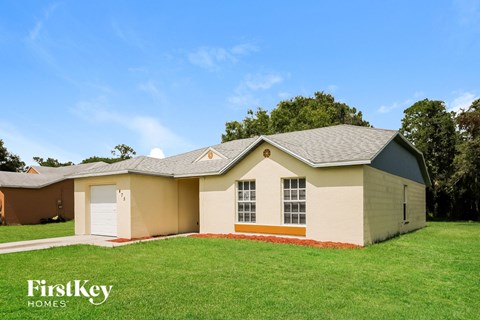 a beige house with a garage and a green lawn