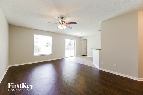 the living room and dining room of an empty house with a ceiling fan