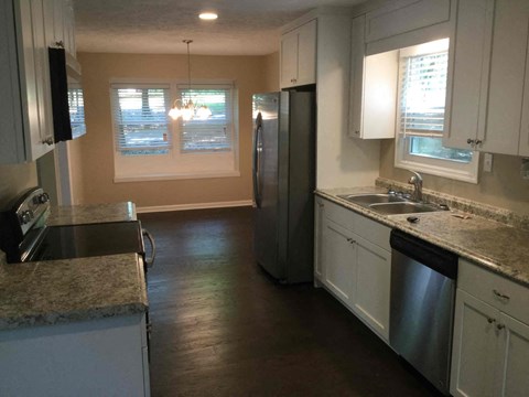 A kitchen with white cabinets and a granite countertop.