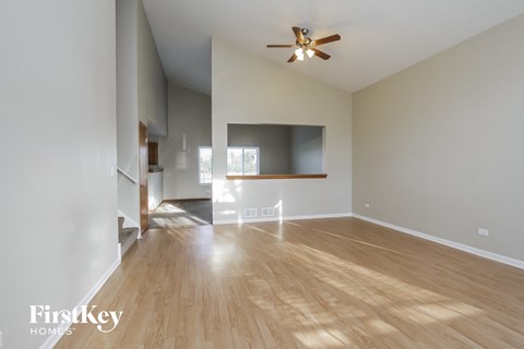 A spacious room with wooden floors and a ceiling fan.