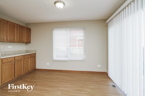 A kitchen with wooden cabinets and a window with blinds.