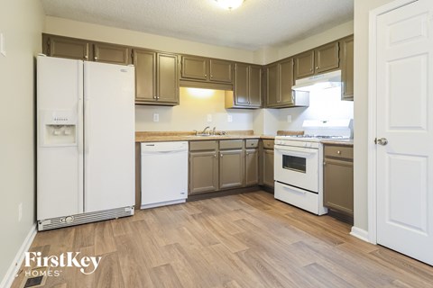 a kitchen with white appliances and wooden flooring