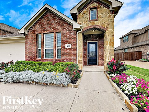 the front of a brick house with flowers on the sidewalk