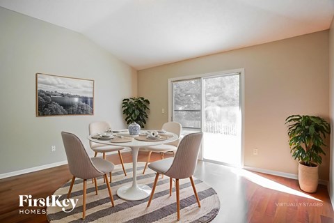 A dining room with a table set for four and a potted plant.