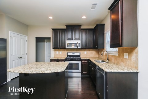 a kitchen with black cabinets and granite counter tops and a stove and microwave