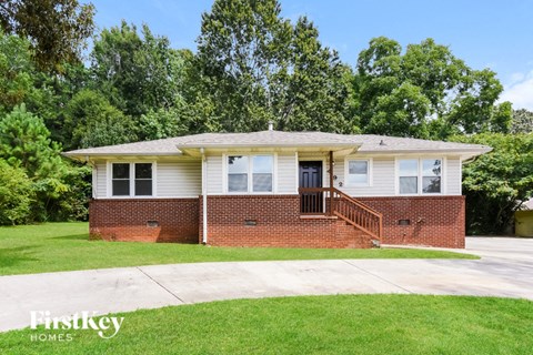 a small brick house with a front porch and a lawn