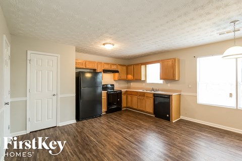 a kitchen with wood flooring and a black refrigerator