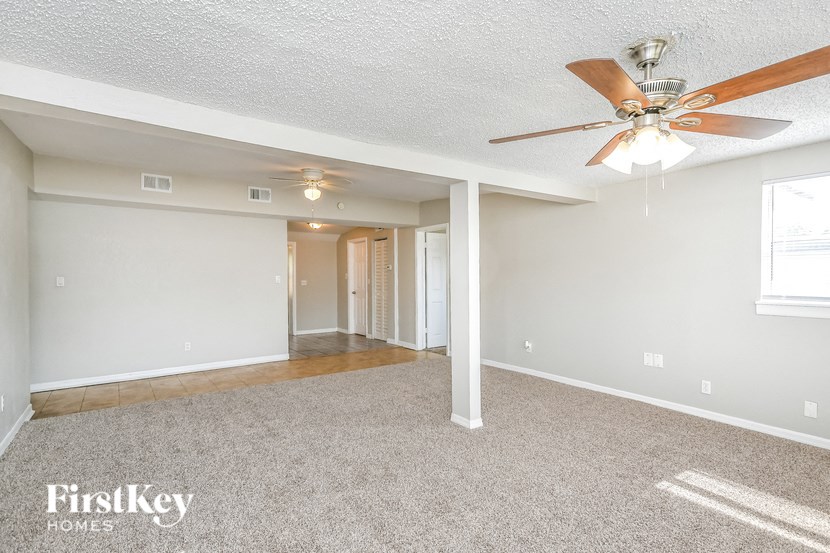 the living room and dining room of an empty house with a ceiling fan