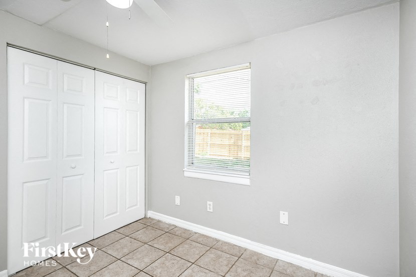a bedroom with two closets and a window and a tiled floor