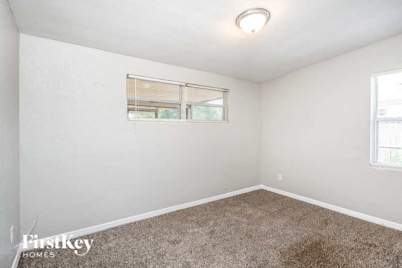 a bedroom with white walls and carpet and a window