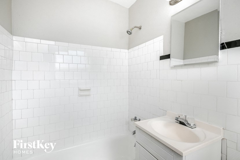 a white bathroom with a sink and a tub and a mirror