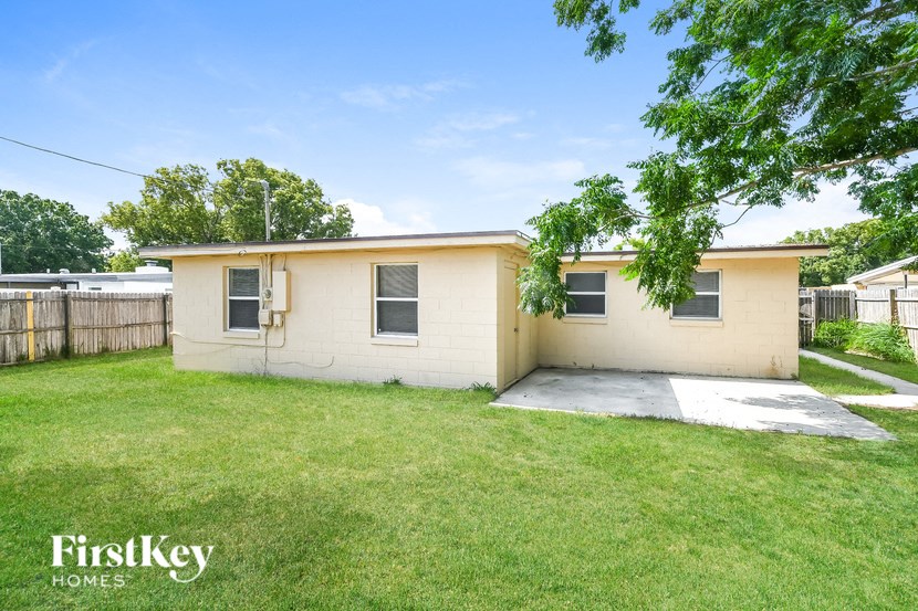 a small tan house with a yard and a tree