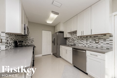 A kitchen with white cabinets and a tile backsplash.