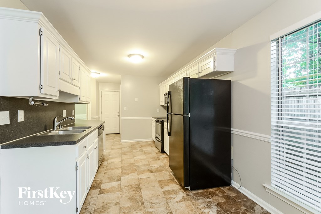 a kitchen with white cabinets and a black refrigerator