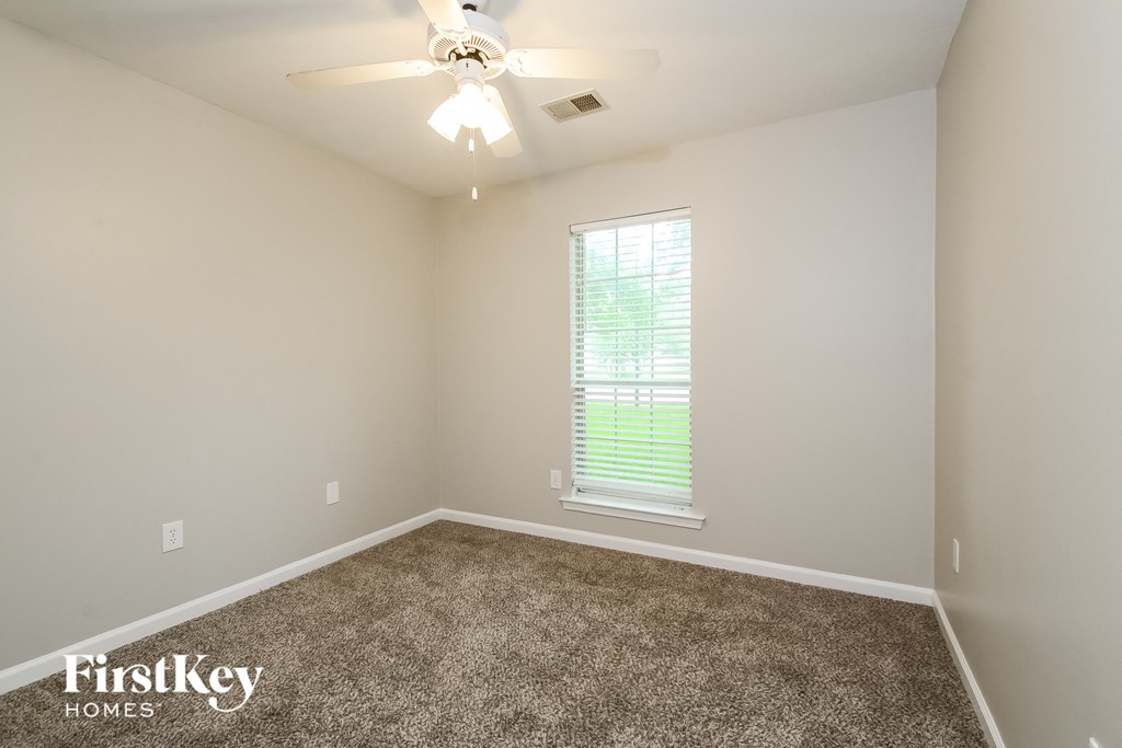 an empty room with carpet and a ceiling fan