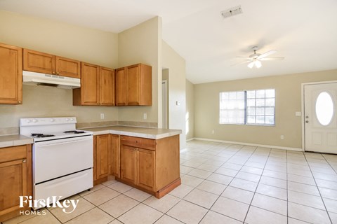 A kitchen with wooden cabinets and a white stove top oven.