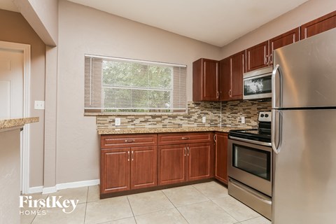 A kitchen with a stainless steel refrigerator and wooden cabinets.